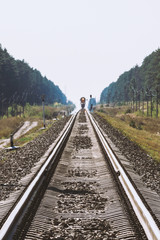 Mystic train travels by rail along forest. Railway traffic light and locomotive on railroad in distance. Mirage on railway track. Atmospheric landscape.