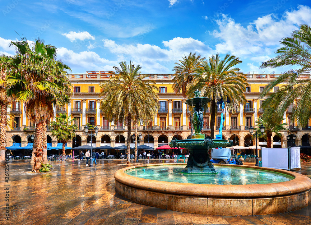 Royal area in Barcelona, Spain. Fountain with statues and high palm trees among traditional Spanish architecture at main central square of old town. Summer landscape with blue sky and clouds. - obrazy, fototapety, plakaty 