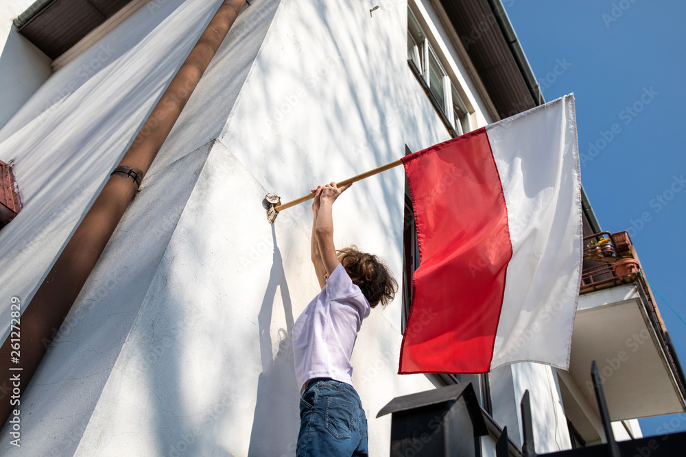 The boy is hanging a flag. Polish National Day of the Third of May, Constitution Day Flag Day, International Labor Day - obrazy, fototapety, plakaty 