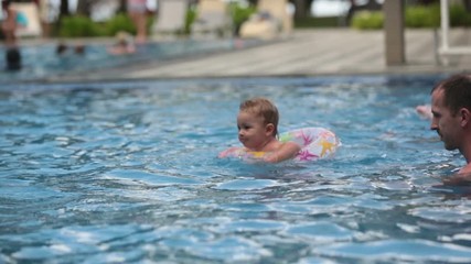 Wall Mural - Adorable happy little child, toddler boy, having fun relaxing and playing in a pool in inflatable ring on sunny day during summer vacation in Mauritius resort