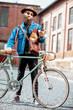 © rh2010 - Portrait of a bearded hipster dressed stylishly with hat and jacket standing with retro bicycle and handgun on the urban background