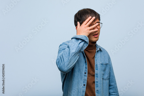 Fotografía Young chinese man embarrassed and laughing at the same time