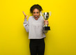 Young fitness black woman celebrating a victory or success. Holding a trophy.