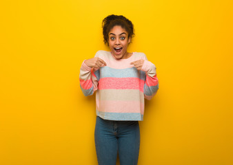 Young black african american girl with blue eyes surprised, feels successful and prosperous