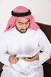 © Mahmoud Rahall - Arab Muslim man sitting on sofa chair and reading the holy Quran