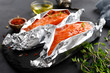 Raw salmon fish fillet in foil on black background