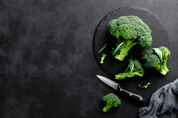 Fresh broccoli florets on black background, top view