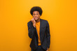 © Asier - Young business african american man over an orange wall biting nails, nervous and very anxious