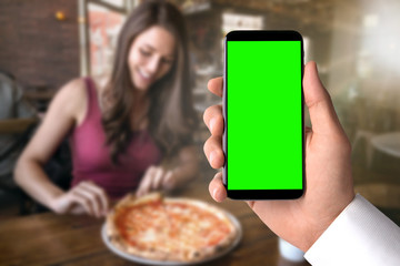 Using smartphone at pizza restaurant to order food, blank screen template