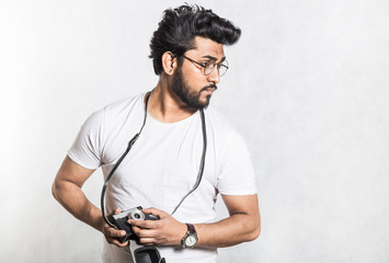 Sticker - Portrait of a handsome young stylish man with beard taking photo on a vintage camera.