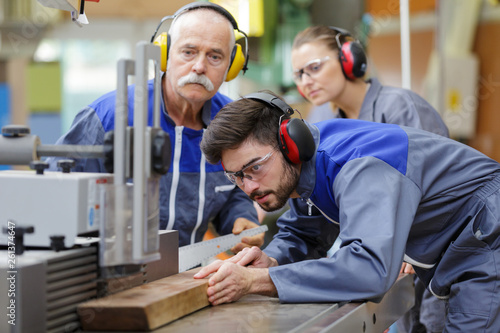 Fotografía carpenter training female apprentice to use plane
