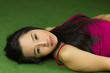 © Nutt - asian women lying on the green grass, a beautiful and dreamy Thai woman laying down on green grass, relaxing while looking at the camera.