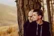 © Alberto Menendez/ADDICTIVE STOCK - cheerful homosexual couple embracing near tree in forest and picturesque view of valley