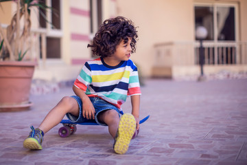 Wall Mural - Little boy with curly hair with skateboard. Children and entertainment concept