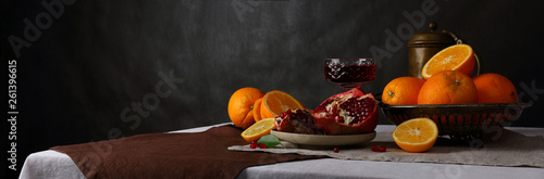Fotografía Panorama with a glass of wine, jug and fruit on a dark background