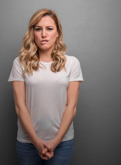 Wall Mural - A young woman is squinting a sour grimace while standing against grey background.