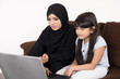 © Mahmoud Rahall - Arab woman teaching her daughter on laptop computer on white background