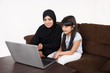 © Mahmoud Rahall - Arab woman teaching her daughter on laptop computer on white background