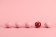 Outstanding red apple among pink painted apples on pastel pink background. Minimal fruit idea concept.