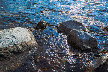 Water streams of a mountain river washing stones covered with colored moss.