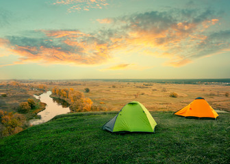Wall Mural - green and orange tent on riverbank on sunny summer day