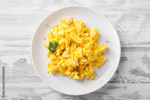 Cuadros en Lienzo Scrambled eggs on white plate over white wooden background.