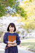 © west_photo - 春の公園で書類を抱きかかえる学生