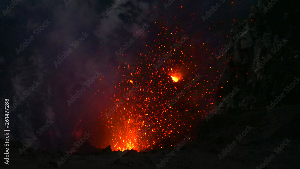 CLOSE UP: Glowing pieces of lava fly up in the air out of an active volcano. - obrazy, fototapety, plakaty 