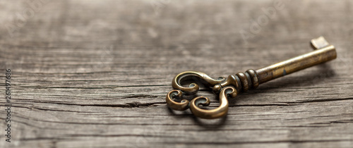 Fotografía Old copper key on wooden table. Copy space for text.