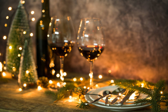 Fototapete - Closeup of red wine on table with Christmas lights. Christmas table and tree.