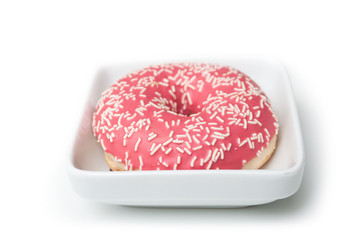 Closeup of pink doughnut in a white bowl on white background