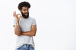 © Cookie Studio - Chill unbothered, positive african american male friend winking in approval and confirmation showing okay gesture with no worries, giving positive opinion, satisfied with perfect plan over gray wall