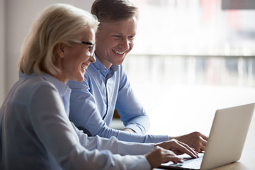 Happy manager and client having conversation at meeting with laptop