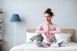 © BestForYou - Woman yoga in the lotus position at home on the bed.