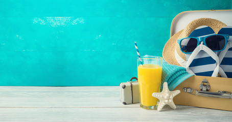 Wall Mural - Summer concept background with cute funny flip flops, suitcase and orange juice on wooden table