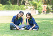 © kwanchaichaiudom - Happy cute students smile and sitting on grass