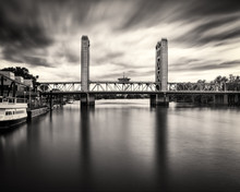 Dramatic Black & White Image Of The Tower Bridge With Clouds Streaking Past.
