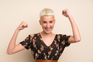 Young woman over isolated wall celebrating a victory