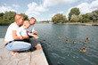 © yurolaitsalbert - happy parents with their little son sitting on the lake pier