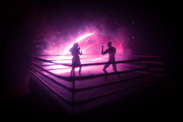 Wall Mural - Man and woman boxing on the ring. Sport concept. Artwork decoration with foggy toned dark background.