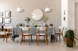 Dining table with fresh plants, glass vessels, candles and white chairs in real photo of living room interior with gallery, lamps and mirror on the wall