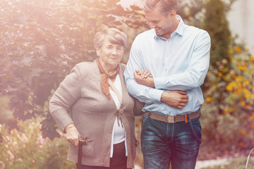 Wall Mural - Smiling son relaxing on outdoor with happy mother with walking stick