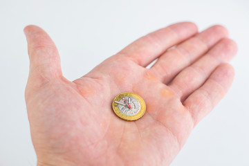 time and money, concept: second, hour and minute hands on a coin of 2 Belarusian rubles, on a person’s hand