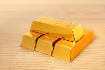 Stacked shiny gold bars on wooden table