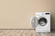 © New Africa - Modern washing machine with laundry near color wall, space for text
