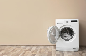 Poster - Modern washing machine with laundry near color wall, space for text