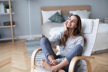 Beautiful happy woman looking at camera and smiling while sitting in a cozy chair.