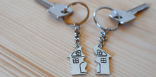 Two Keys With Splitted Or Broken Key Rings With Pendant In Shape Of House Divided In Two Parts On Wooden Background With Copy Space. Dividing House When Divorce, Division Of Property, Real Estate Heri