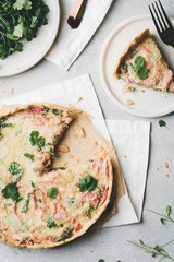 A piece of homemade cheese quiche or pie sprinkled with parsley on gray concrete background. Vintage toned. French cuisine