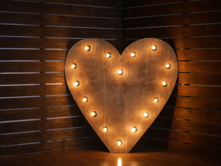 wooden heart with light bulbs on the contour on the background of wooden boards. in the studio. horizontally